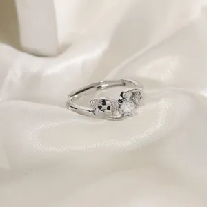 Close-up of silver puppy ring with sparkling zircon stone on white silk background