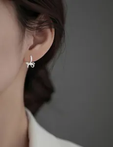 Close-up detail of a sparkling silver bow earring featuring delicate micro-pave zirconia