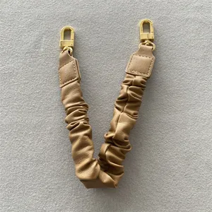 Nahaufnahme von khakifarbenem Leder-Handtaschenriemen mit Goldschließen