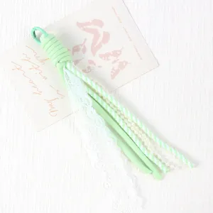 Light green paracord phone charm with white lace, striped ribbon, pearl beads for DIY craft use.