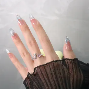 Gros plan d'une bague chat argentée avec fleur de cerisier rose au doigt