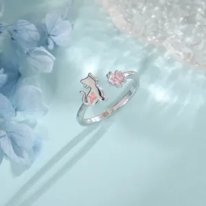 Détail macro d'une bague ouverte en argent avec chat et fleur de cerisier rose S925