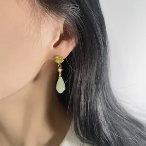Detail view of Chinese style gold fan earrings with light green jade teardrop pendant