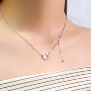 Primer plano del collar con colgante de gato de circón rosa en la zona clavícula.