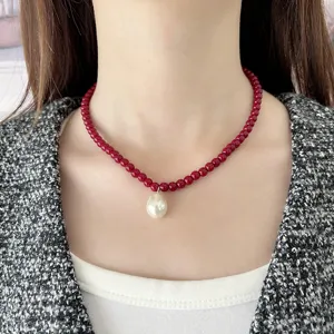 Primer plano de un collar con cuentas rojas y colgante de perla en una modelo