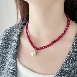 Vista detallada elegante del collar de cuentas rojas con colgante de perla blanca