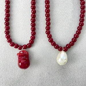 Detalle de collares de cuentas rojas con perla blanca y colgantes barrocos de vidrio