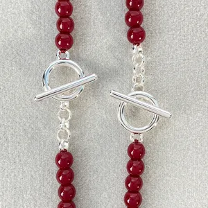Detalle de los cierres de palanca plateados en un elegante collar de cuentas rojas