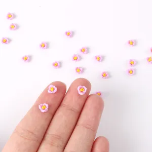 Piccole rose in resina rosa per nail art mostrate sulle dita come riferimento