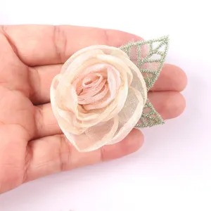 Handcrafted organza camellia flower DIY accessory with green leaf for apparel and headwear.