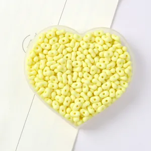 Close-up detail of pale yellow peanut-shaped two-hole beads in a heart-shaped tray
