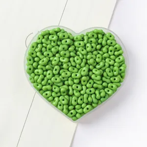 Detailed macro view of vibrant green peanut-shaped two-hole beads for DIY jewelry making.