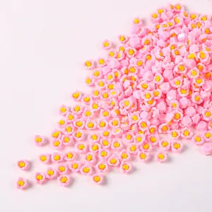 Dettaglio di piccoli fiori rosa in resina con centro giallo per nail art e fai-da-te.