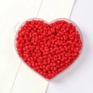 Detail view of vibrant red peanut-shaped dual-hole beads in a heart container.