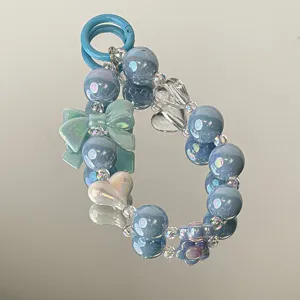 Macro view of blue pearlescent acrylic beads and green bow charm on a mirror