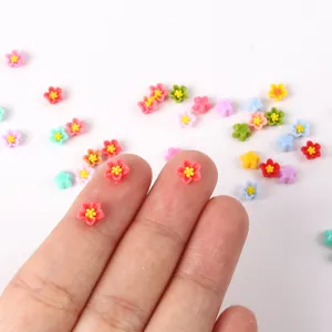 Détail de cabochons de fleurs en résine miniature montrant la taille sur les doigts pour ongles.