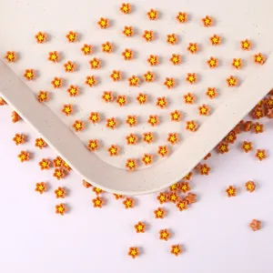 Gros plan détaillé de petites fleurs en résine de 6 mm orange avec un cœur jaune pour le nail art.