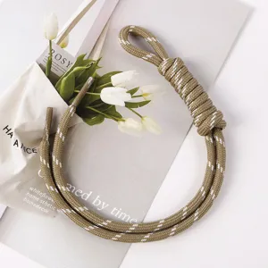 Detailed view of a handcrafted khaki braided rope bag charm with decorative white accents