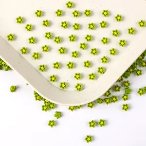 Gros plan detail cabochons de fleurs en resine verte pour ongles, ideal pour creations DIY.