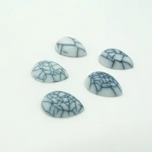 Détail macro de perles en résine en forme de larme blanches avec motif craquelé noir
