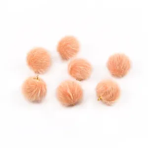 Dettaglio macro di pompon in finta pelliccia di visone pesca 17 mm con asole dorate per fai da te
