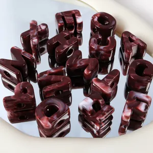 Primo piano dettagliato di perle di lettere in acrilico marmorizzato rosso scuro con fori grandi.