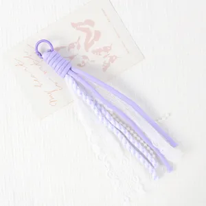 Detailed view of the purple paracord phone charm with white lace and pearl DIY accessories.