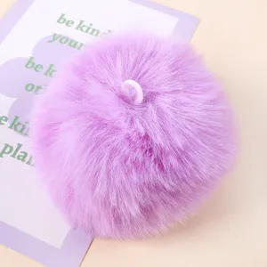 Purple faux fur pom pom close up, fluffy texture and hanging loop detail for DIY crafts.
