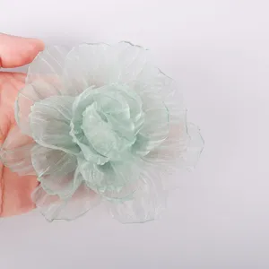 Detailed view of light green sheer organza fabric flower accessory for DIY crafts and apparel.