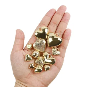 Vue de détail de pendentifs cœur dorés et breloques rondes pour fabrication de bijoux DIY.