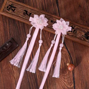 Gros plan sur d'élégantes pinces à cheveux fleur rose avec pompons et perles.