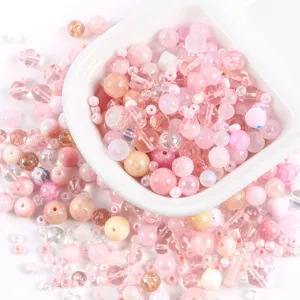 Detailed top-down view of various mixed pink glass and stone beads for DIY jewelry making
