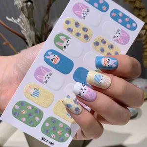 Macro-weergave van kleurrijke paashaas en ei nagelstickers op gemanicuurde handen.