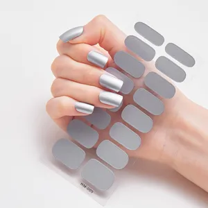 Detalle de pegatinas de uñas metálicas plateadas aplicadas en la mano