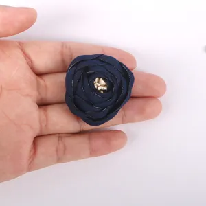 Vue en main d'une fleur rose en tissu 3D bleu marine pour la décoration de vêtements.