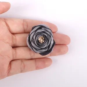 Vue détaillée d'un accessoire fleur de rose en tissu 3D gris fait main tenu pour référence