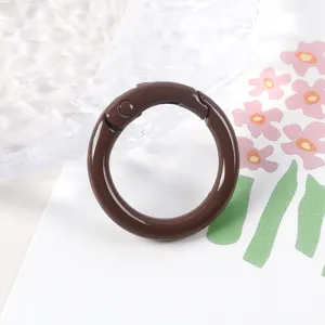 Detalle mosquetón de anillo de resorte de metal marrón para correas de bolsos y accesorios de joyería.