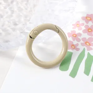 Primer plano detalle de un cierre de anillo de resorte de metal pintado de beige, liso.