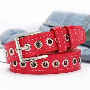 Primer plano de cinturón punk rojo con ojales metálicos plateados y hebilla de pasador