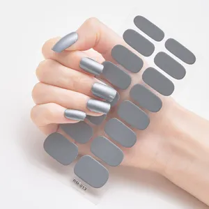 Detalle de 16 pegatinas de uñas de plata metálica aplicadas en una mano y una lámina