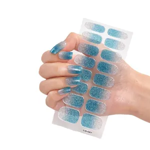 Blaue und silberne Glitzer-Nagelsticker mit Farbverlauf auf Hand und Stickerbogen