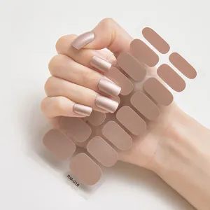 Primer plano detallado de pegatinas de uñas color moca metálico en uñas y la hoja