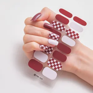 Detalle macro de pegatinas de uñas de tablero de ajedrez rojo en uñas naturales largas