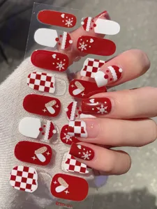 Detailaufnahme von weihnachtlichen Nagelstickern mit roten und weißen Schneeflocken-Motiven