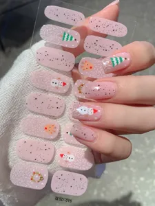 Nahaufnahme von Weihnachts-Nagelstickern mit Schneemann- und Baum-Motiven auf Rosa