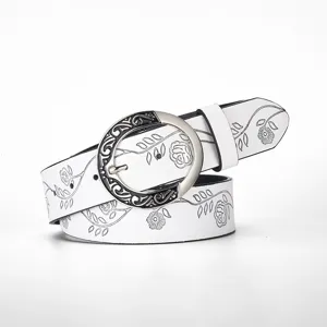 Close-up of white retro leather belt with floral embossing and ornate metal buckle