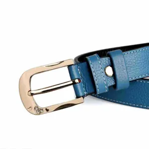 Primer plano detallado de cinturón de mujer de cuero azul con hebilla dorada y brillantes de estrás.