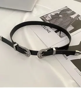 Detailed view of vintage black belt with ornate silver-toned double buckles and engraved tips.