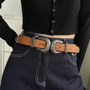 Detailed view of a retro carved double buckle leather belt paired with navy denim jeans