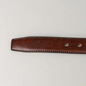 Gros plan du bout d'une ceinture en cuir marron texturé avec des coutures détaillées